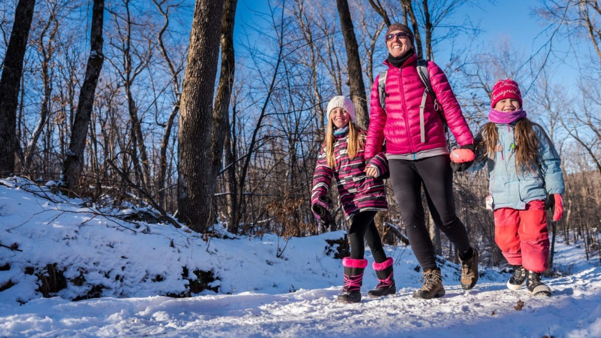 A woman and her two daughters walking hand in hand.